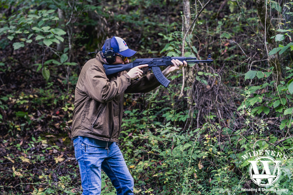 photo of a man shooting an ak47 rifle in the woods illustrating the history of the ak-47