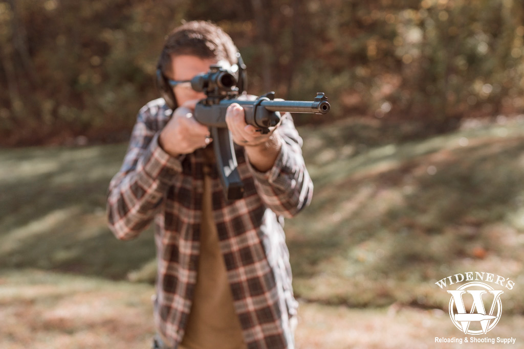 a photo of a man shooting a rimfire rifle outdoors
