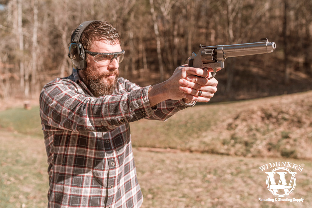 a photo of a man shooting a double action revolver outdoors