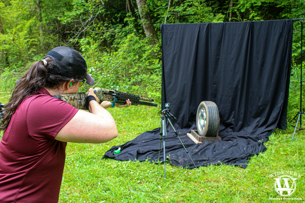 a photo of a woman with a shotgun outdoors